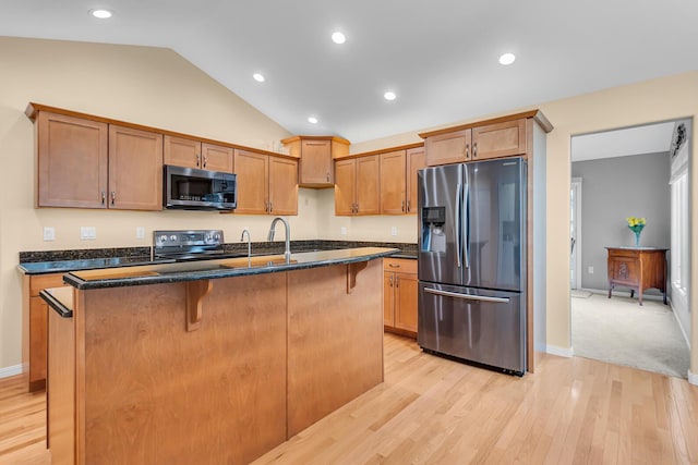4268 Fairway Ln, Jackson, MI 49201 - kitchen featuring appliances with stainless steel finishes, an island with sink, light wood-type flooring, lofted ceiling, and a breakfast bar area