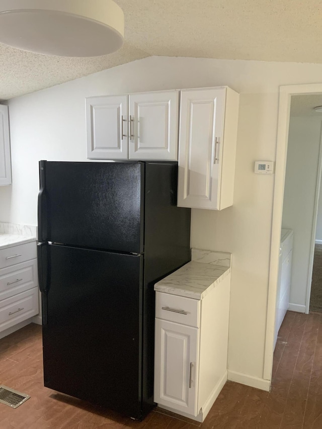 8356 Constitution Blvd, Cadillac, MI 49601 - kitchen featuring freestanding refrigerator, light countertops, white cabinetry, a textured ceiling, and lofted ceiling