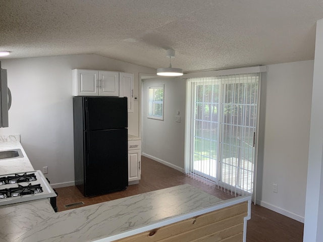 8356 Constitution Blvd, Cadillac, MI 49601 - kitchen with freestanding refrigerator, dark wood finished floors, light countertops, white cabinetry, and vaulted ceiling