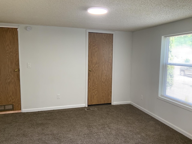 8356 Constitution Blvd, Cadillac, MI 49601 - unfurnished room with a textured ceiling, dark carpet, a smoke detector, and plenty of natural light