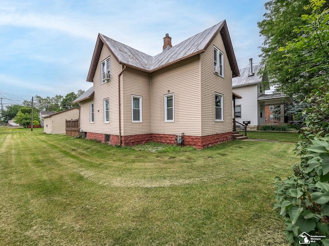 606 E 3rd St, Monroe, MI 48161 - view of side of home with a metal roof, a lawn, a chimney, and a standing seam roof