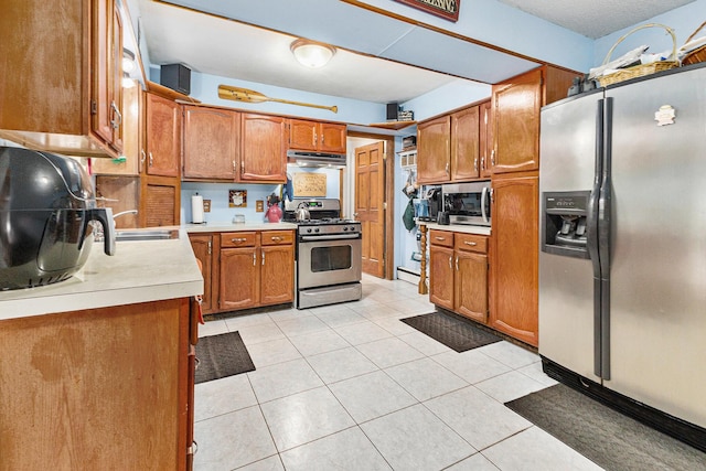 116 E Beech St, Fruitport, MI 49415 - kitchen with stainless steel appliances, brown cabinetry, light countertops, under cabinet range hood, and light tile patterned flooring
