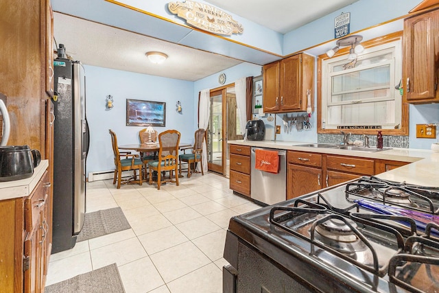 116 E Beech St, Fruitport, MI 49415 - kitchen with appliances with stainless steel finishes, brown cabinets, light countertops, and light tile patterned flooring