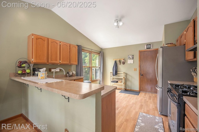 33550 24 Mile Rd, Chesterfield, MI 48047 - kitchen with stainless steel gas range, a peninsula, vaulted ceiling, light wood-style floors, and light countertops