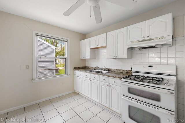 561 E Bennett Ave, Ferndale, MI 48220 - kitchen with gas range gas stove, under cabinet range hood, white cabinets, dark countertops, and backsplash