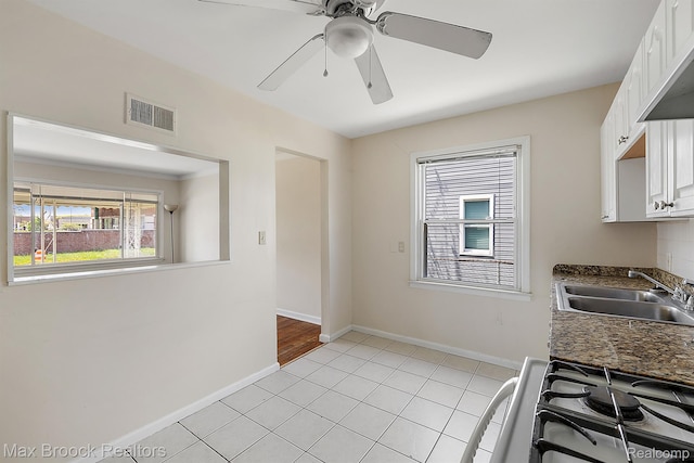 561 E Bennett Ave, Ferndale, MI 48220 - kitchen featuring white gas range, white cabinets, ceiling fan, light tile patterned floors, and dark countertops