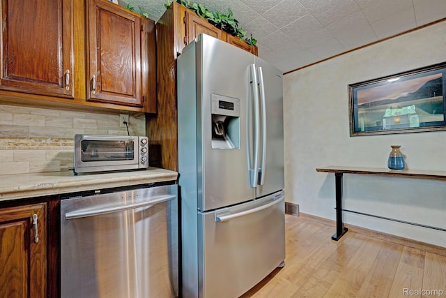 4030 Rollins Ave, Waterford, MI 48329 - kitchen featuring stainless steel appliances, tasteful backsplash, light wood finished floors, and brown cabinets