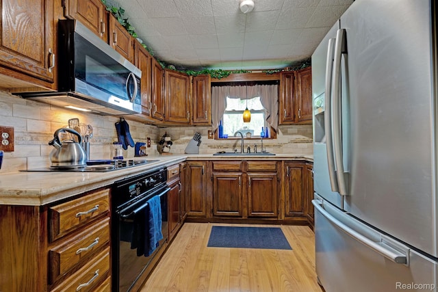 4030 Rollins Ave, Waterford, MI 48329 - kitchen with black appliances, light wood-type flooring, light countertops, decorative backsplash, and brown cabinetry