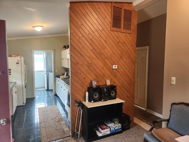 7965 Elm St, Taylor, MI 48180 - kitchen with freestanding refrigerator, white cabinets, dark tile patterned floors, ornamental molding, and wood walls