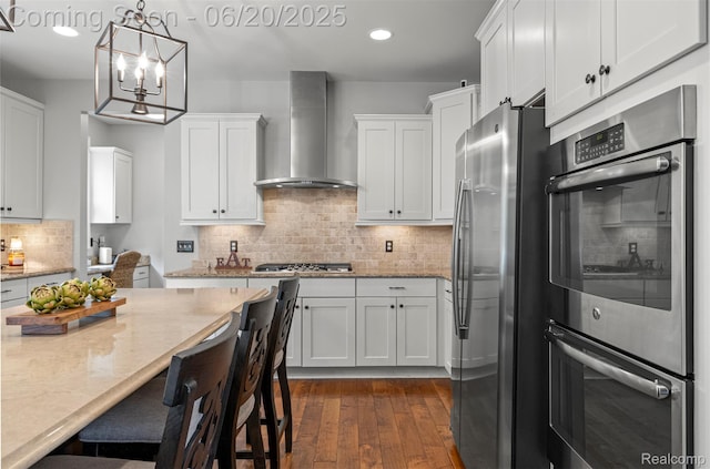 23736 Point O Woods Ct, South Lyon, MI 48178 - kitchen featuring wall chimney exhaust hood, appliances with stainless steel finishes, white cabinetry, dark wood-style flooring, and light stone counters