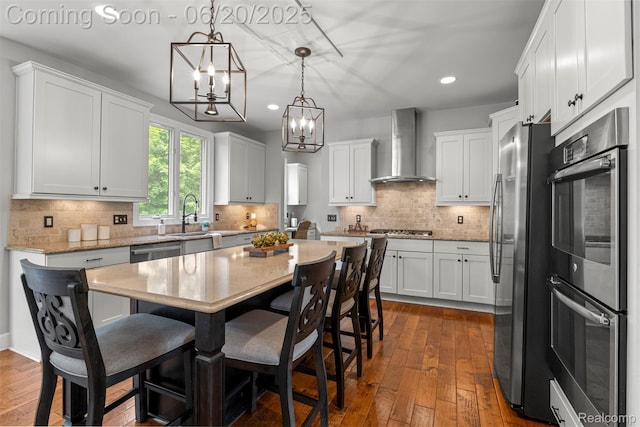 23736 Point O Woods Ct, South Lyon, MI 48178 - kitchen with wall chimney exhaust hood, appliances with stainless steel finishes, a chandelier, recessed lighting, and dark wood-style floors