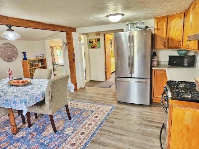 350 S Catalpa Ave, White Cloud, MI 49349 - kitchen with stainless steel appliances, light wood finished floors, brown cabinets, and a textured ceiling