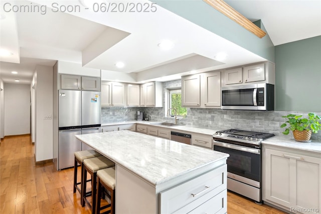 459 N Elms Rd, Flushing, MI 48433 - kitchen featuring stainless steel appliances, tasteful backsplash, light wood-style flooring, a kitchen island, and a breakfast bar area