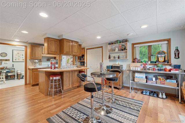 459 N Elms Rd, Flushing, MI 48433 - kitchen featuring light countertops, open shelves, light wood-style flooring, a kitchen bar, and a drop ceiling