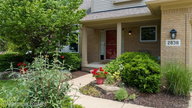 2836 Otter Ct, Wixom, MI 48393 - doorway to property featuring brick siding, a shingled roof, and a porch