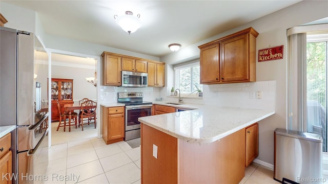 2836 Otter Ct, Wixom, MI 48393 - kitchen with stainless steel appliances, a peninsula, healthy amount of natural light, and brown cabinetry