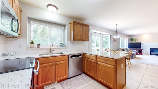 2836 Otter Ct, Wixom, MI 48393 - kitchen with stainless steel appliances, a peninsula, open floor plan, tasteful backsplash, and a glass covered fireplace