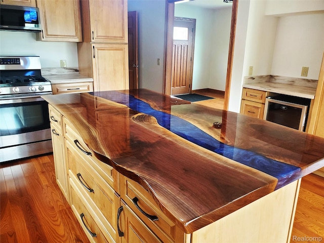 115 Choctaw Trl, Prudenville, MI 48651 - kitchen with stainless steel appliances, butcher block countertops, wine cooler, wood finished floors, and a center island