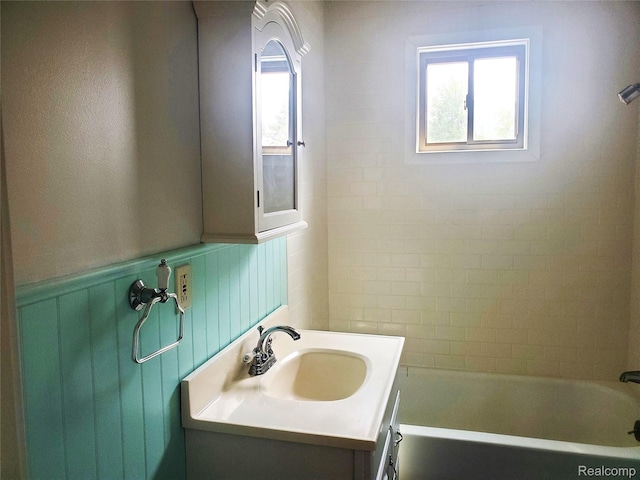 115 Choctaw Trl, Prudenville, MI 48651 - bathroom featuring vanity, a wainscoted wall, and shower / bathtub combination