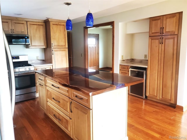 115 Choctaw Trl, Prudenville, MI 48651 - kitchen featuring stainless steel appliances, wine cooler, wood finished floors, dark countertops, and decorative light fixtures