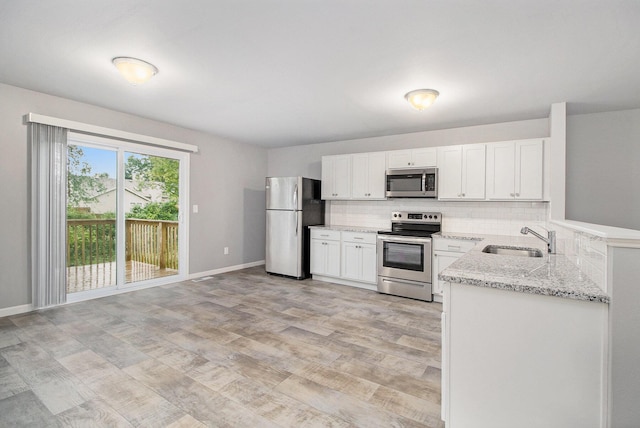 7216 Heartwood Ct, Portage, MI 49002 - kitchen featuring stainless steel appliances, tasteful backsplash, light stone countertops, white cabinets, and light wood finished floors