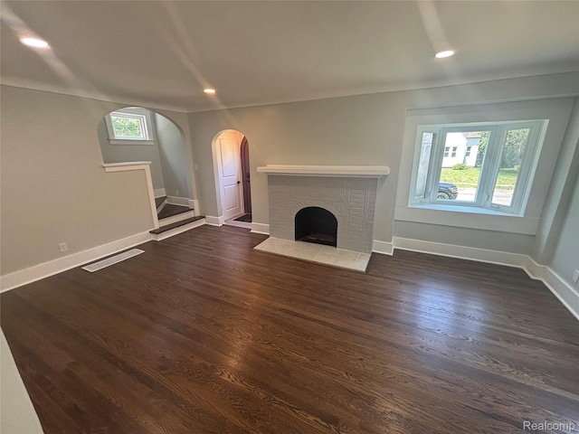 910 Spence St, Southfield, MI 48340 - unfurnished living room featuring arched walkways, a brick fireplace, dark wood-style flooring, recessed lighting, and stairway