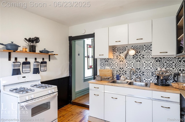 1200 Porter St, Detroit, MI 48226 - kitchen featuring white gas stove, open shelves, backsplash, light wood-style floors, and white cabinetry