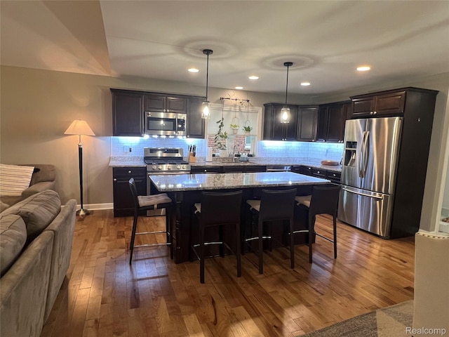 23540 Wilson Ave, Dearborn, MI 48128 - kitchen featuring appliances with stainless steel finishes, dark wood-type flooring, open floor plan, a center island, and tasteful backsplash