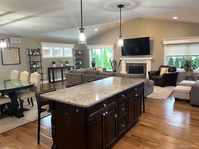 23540 Wilson Ave, Dearborn, MI 48128 - kitchen with a kitchen bar, open floor plan, vaulted ceiling, a fireplace, and light wood-style flooring