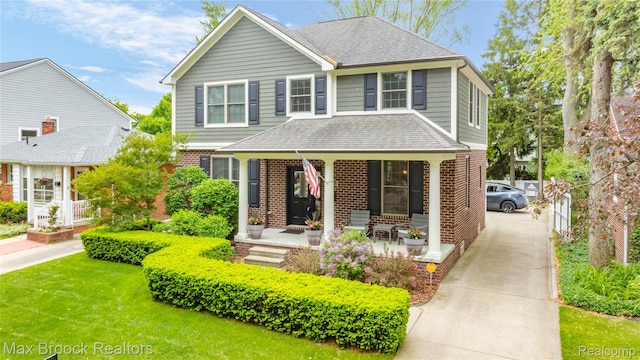 2534 Buckingham Ave, Birmingham, MI 48009 - traditional-style home featuring a porch, brick siding, roof with shingles, concrete driveway, and a front lawn
