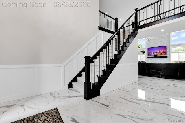 56727 Via Carlotta, Shelby Twp, MI 48042 - stairway with a decorative wall, marble tiled floors, a high ceiling, and wainscoting