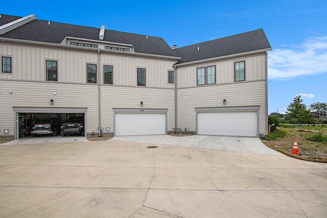 994 Harbor Dr E, Saint Joseph, MI 49085 - rear view of property featuring driveway, a garage, board and batten siding, and roof with shingles