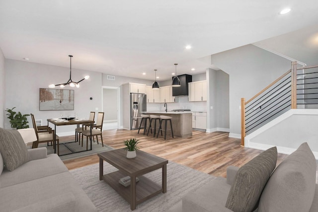 994 Harbor Dr E, Saint Joseph, MI 49085 - living area with stairs, a chandelier, light wood finished floors, and recessed lighting