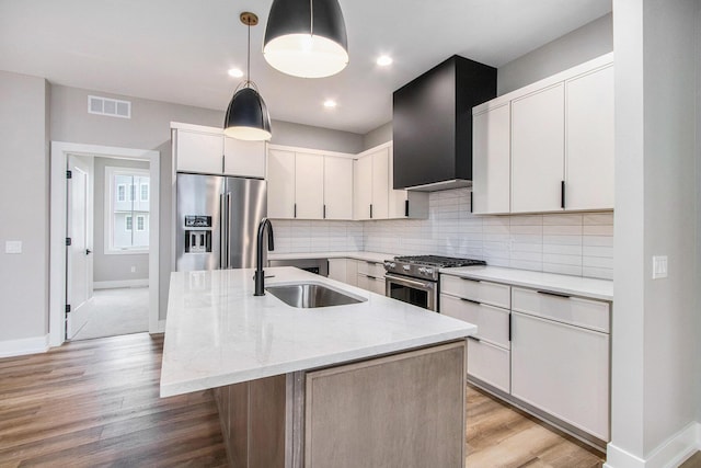 994 Harbor Dr E, Saint Joseph, MI 49085 - kitchen featuring stainless steel appliances, light wood finished floors, a center island with sink, decorative backsplash, and light stone countertops