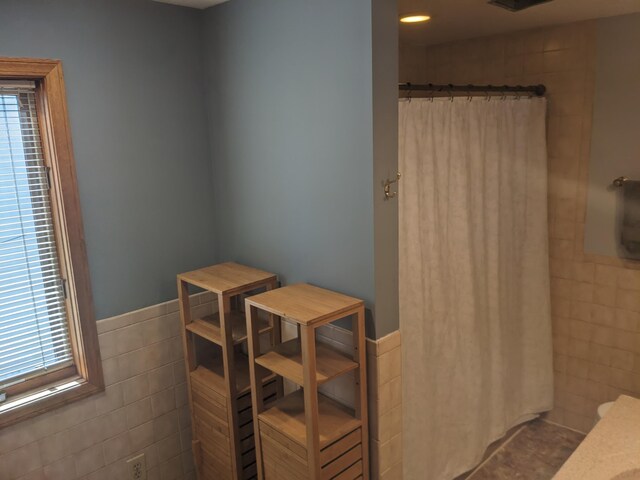 539 Sunset Ln, East Lansing, MI 48823 - full bathroom with tile walls, a shower with curtain, healthy amount of natural light, wainscoting, and tile patterned floors