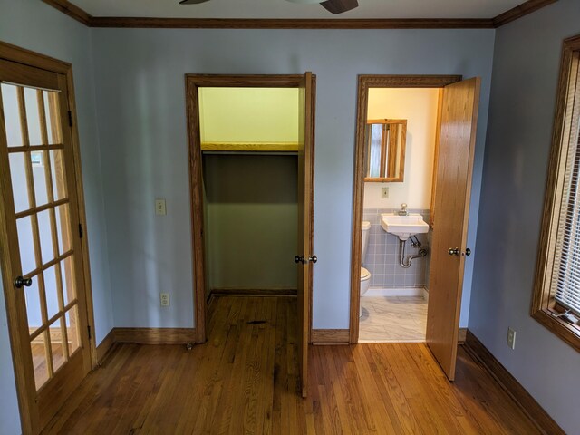 539 Sunset Ln, East Lansing, MI 48823 - unfurnished bedroom featuring wood finished floors, crown molding, french doors, ensuite bathroom, and multiple windows
