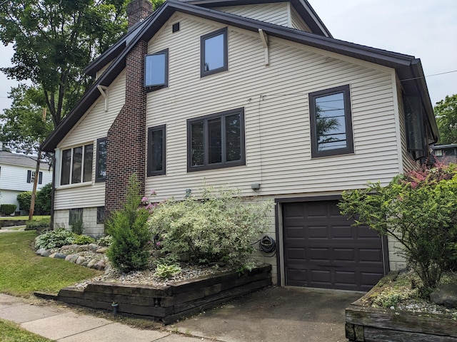 539 Sunset Ln, East Lansing, MI 48823 - view of home's exterior with an attached garage, driveway, and a chimney