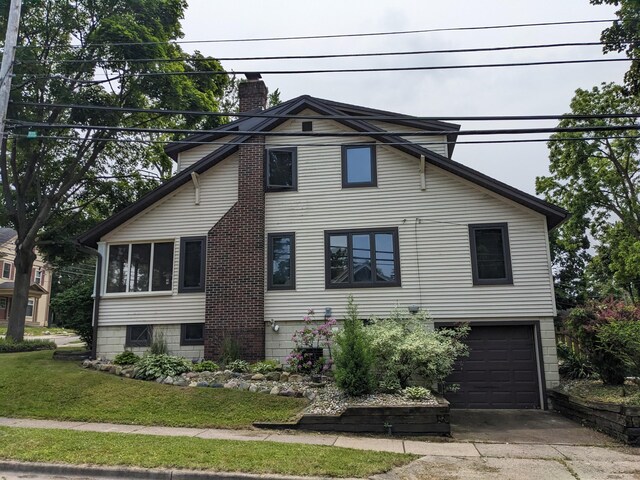 539 Sunset Ln, East Lansing, MI 48823 - view of front of home with a chimney, a garage, driveway, and a front yard
