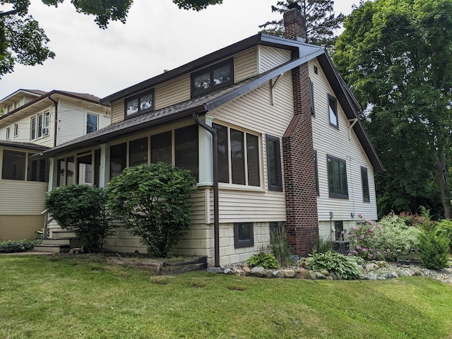 539 Sunset Ln, East Lansing, MI 48823 - view of side of home with a sunroom, a chimney, and a yard