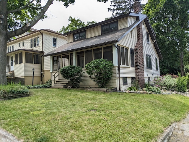 539 Sunset Ln, East Lansing, MI 48823 - view of front facade with a sunroom, a chimney, a shingled roof, and a front lawn