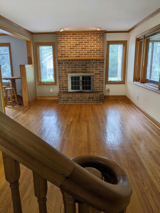 539 Sunset Ln, East Lansing, MI 48823 - unfurnished living room featuring ornamental molding, hardwood / wood-style flooring, and a brick fireplace