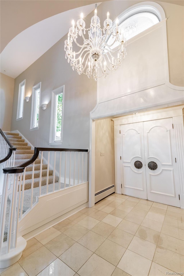 19891 Parke Ln, Grosse Ile, MI 48138 - entryway featuring baseboard heating, stairs, a chandelier, light tile patterned flooring, and a towering ceiling