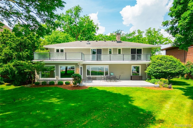 19891 Parke Ln, Grosse Ile, MI 48138 - back of house featuring a balcony, a chimney, a lawn, brick siding, and a patio area
