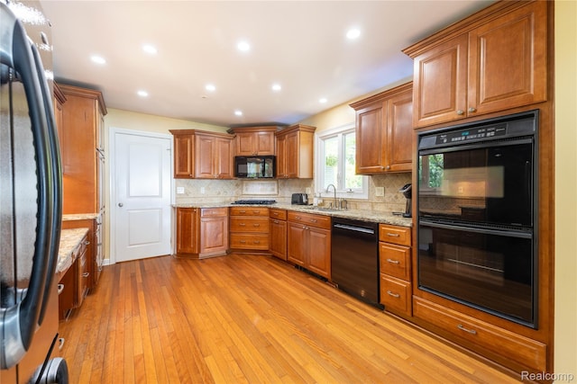 19891 Parke Ln, Grosse Ile, MI 48138 - kitchen featuring black appliances, light wood-style floors, brown cabinets, tasteful backsplash, and recessed lighting