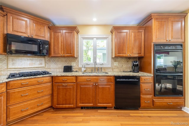 19891 Parke Ln, Grosse Ile, MI 48138 - kitchen featuring black appliances, light wood-style floors, light stone countertops, brown cabinetry, and recessed lighting