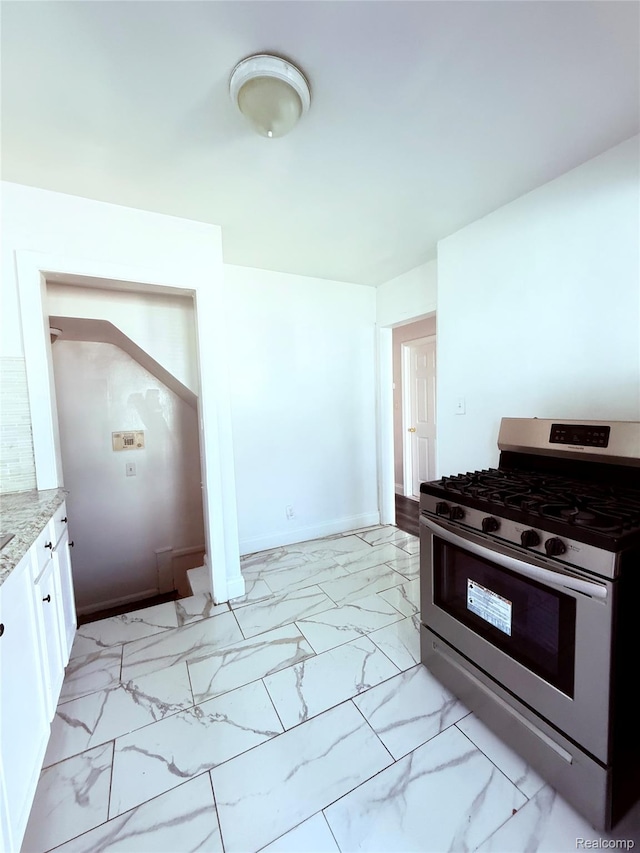 9941 Minock St, Detroit, MI 48228 - kitchen with stainless steel range with gas cooktop, light marble finish flooring, white cabinets, and light stone countertops