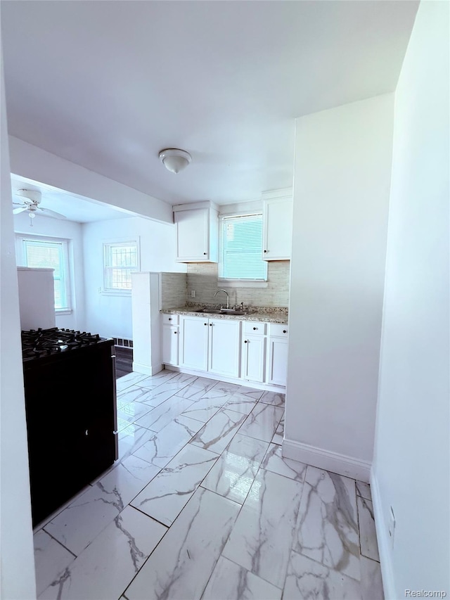 9941 Minock St, Detroit, MI 48228 - kitchen with black range with gas cooktop, light stone countertops, white cabinetry, tasteful backsplash, and light marble finish floors