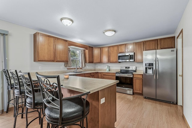 1860 Partridge Ln, Kalamazoo, MI 49009 - kitchen featuring stainless steel appliances, a peninsula, a kitchen breakfast bar, and light wood-style floors