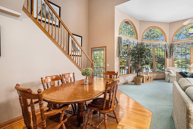 11683 Fair Lk, Delton, MI 49046 - dining space featuring stairs, a towering ceiling, and wood finished floors