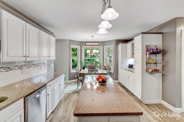 278 Caravan Rd, Norton Shores, MI 49441 - kitchen featuring stainless steel dishwasher, light wood-type flooring, tasteful backsplash, light stone counters, and a textured ceiling